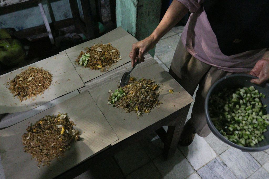 Istri Suwarto menaburkan acar ke nasi goreng di kawasan Pisangan, Ciputat Timur, Tangerang Selatan, Jumat (14/10/2022).