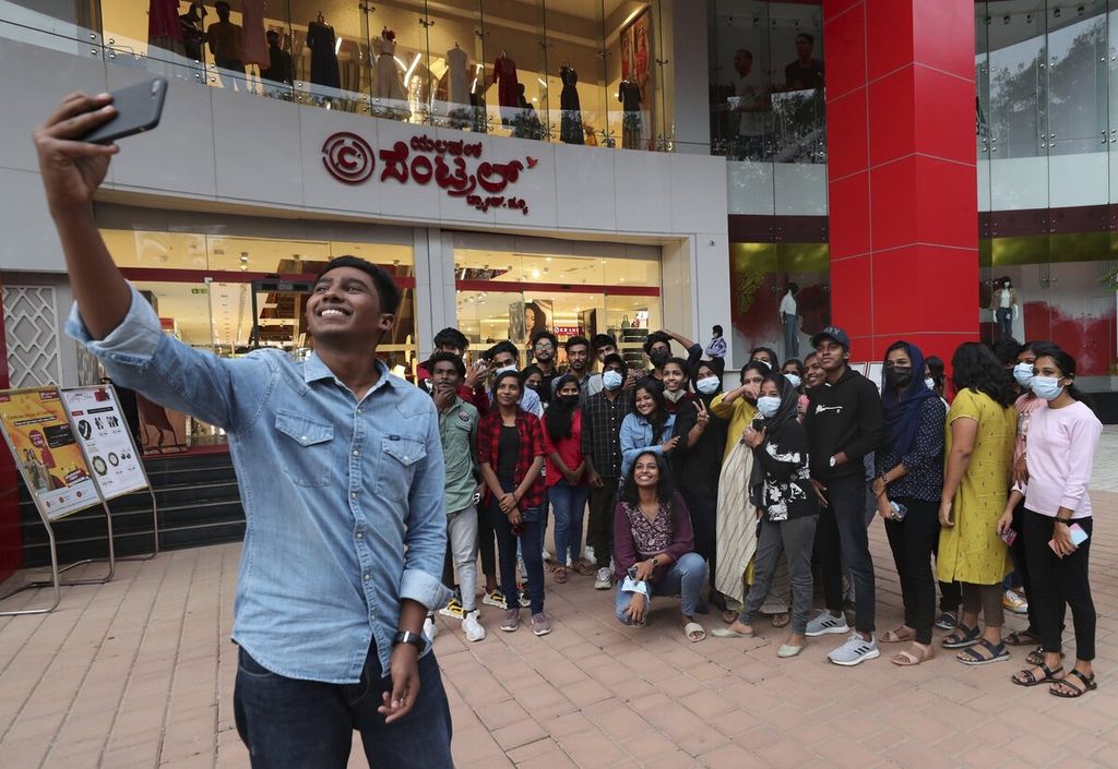 Sekelompok anak muda yang sebagian mengenakan masker berswafoto di luar pusat perbelanjaan di Bengaluru, ibu kota Negara Bagian Karnataka, India, Kamis (2/12/2021).