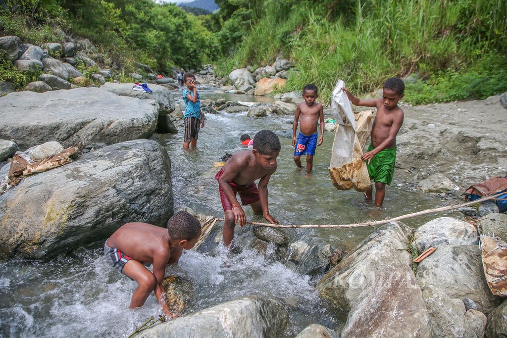 Anak-anak bermain di Sungai Dobokurung yang berhulu di cagar alam Pegunungan Cycloop melintasi kawasan Doyo Baru, Sentani, Jayapura, Minggu (28/11/2021). Pada tahun 2019, terjadi banjir bandang di sungai Dobokurung yang menyebabkan 105 orang tewas dan kerugian mencapai Rp 506 miliar. 