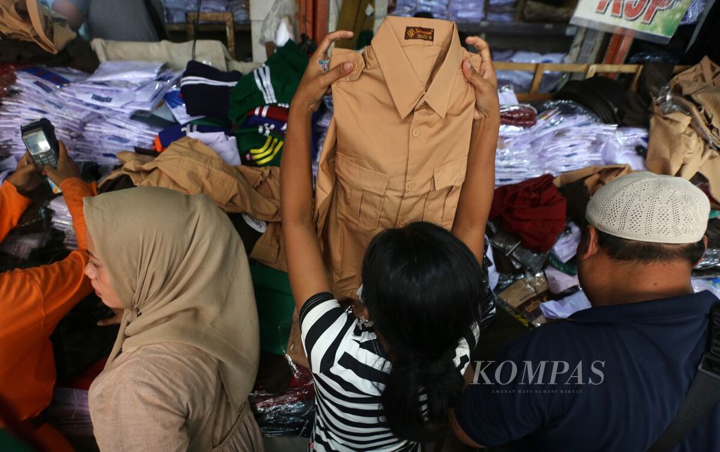 Warga memilih seragam sekolah untuk anaknya di Pasar Jatinegara, Jakarta Timur, Selasa (4/1/2022).