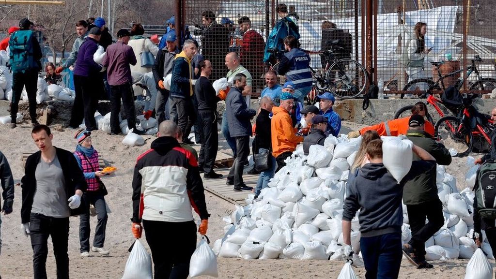 Warga bahu-membahu membawa kantong berisi pasir yang digunakan sebagai barikade pertahanan dan untuk pos pemeriksaan di Odessa, Ukraina, Jumat (25/3/2022). 
