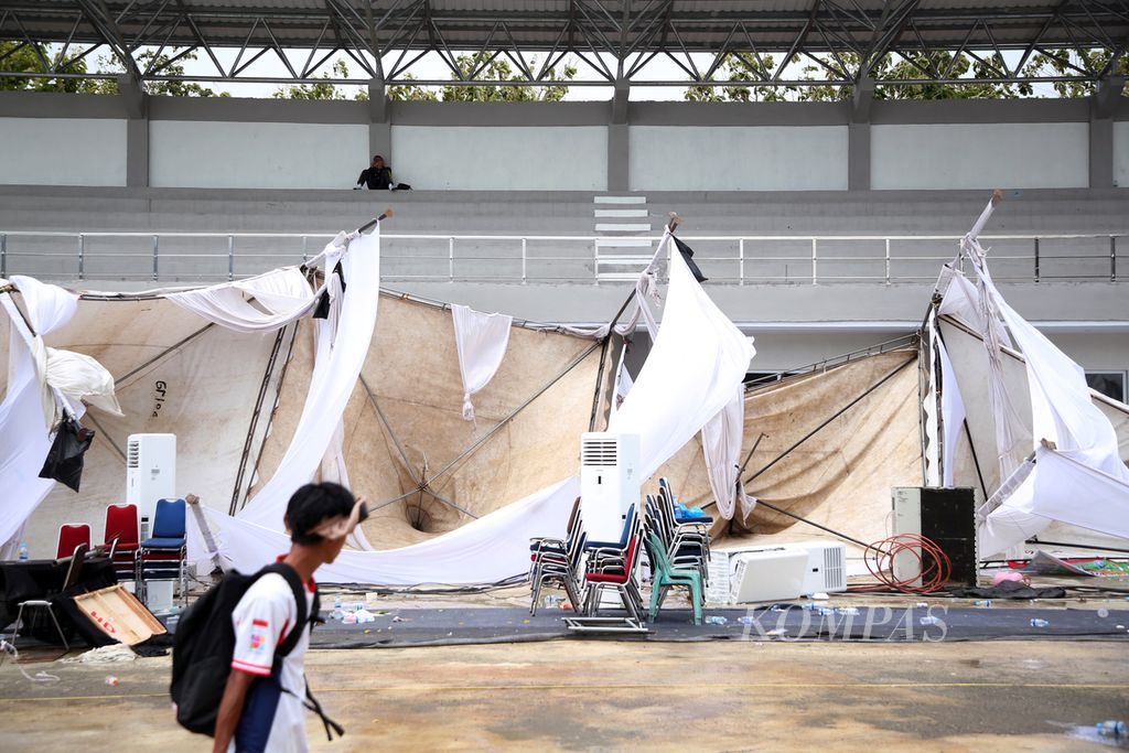 Atlet pulang dengan melewati tenda tim peserta yang bertumbangan seusai Lapangan Panahan PON Aceh-Sumut 2024 di Kompleks Stadion Harapan Bangsa, Banda Aceh, Rabu (18/9/2024), dihantam hujan badai sekitar pukul 12.00. 