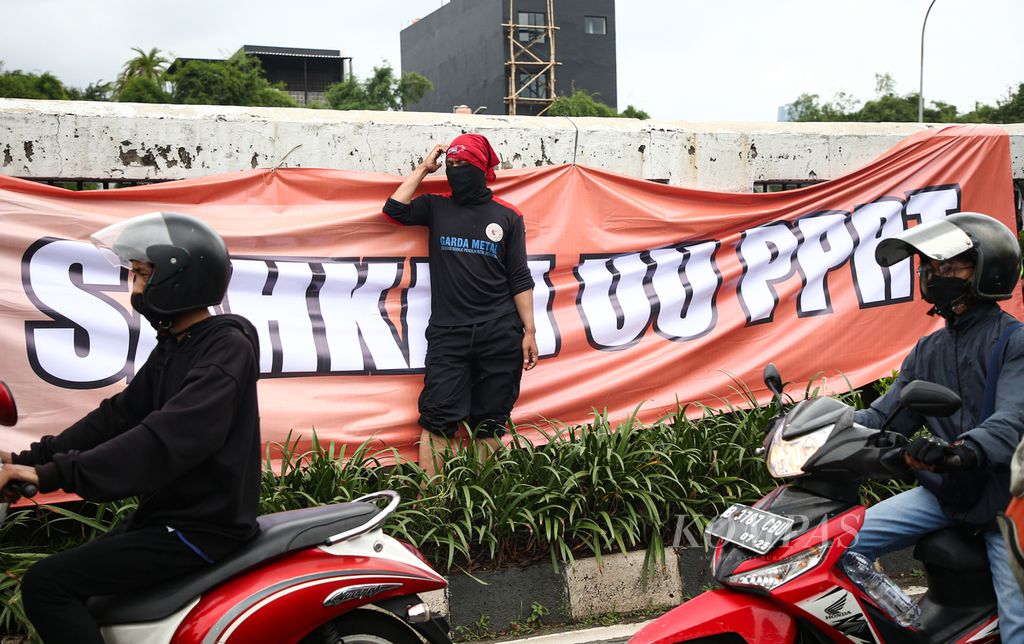 Spanduk tuntutan terkait pengesahan Rancangan Undang-undang Perlindungan Pekerja Rumah Tangga dibentang di pagar pembatas jalan tol di depan gedung DPR RI Jakarta, Jumat (14/1/2022).