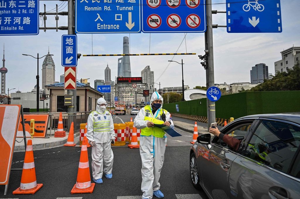 Seorang polisi (tengah), dengan memakai baju alat pelindung diri, mengatur akses ke terowongan menuju Distrik Pudong, yang ditutup secara total (<i>lockdown</i>), guna mengendalikan penularan wabah Covid-19 di Shanghai, China, Senin (28/3/2022). 