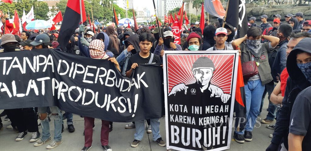 Kumpulan massa dari berbagai serikat buruh dan mahasiswa berorasi di samping Patung Arjuna Wijaya, Jakarta, Rabu (1/5/2019), untuk memperingati Hari Buruh Internasional 2019. Mereka menuntut penghapusan PP No 78 Tahun 2015.
