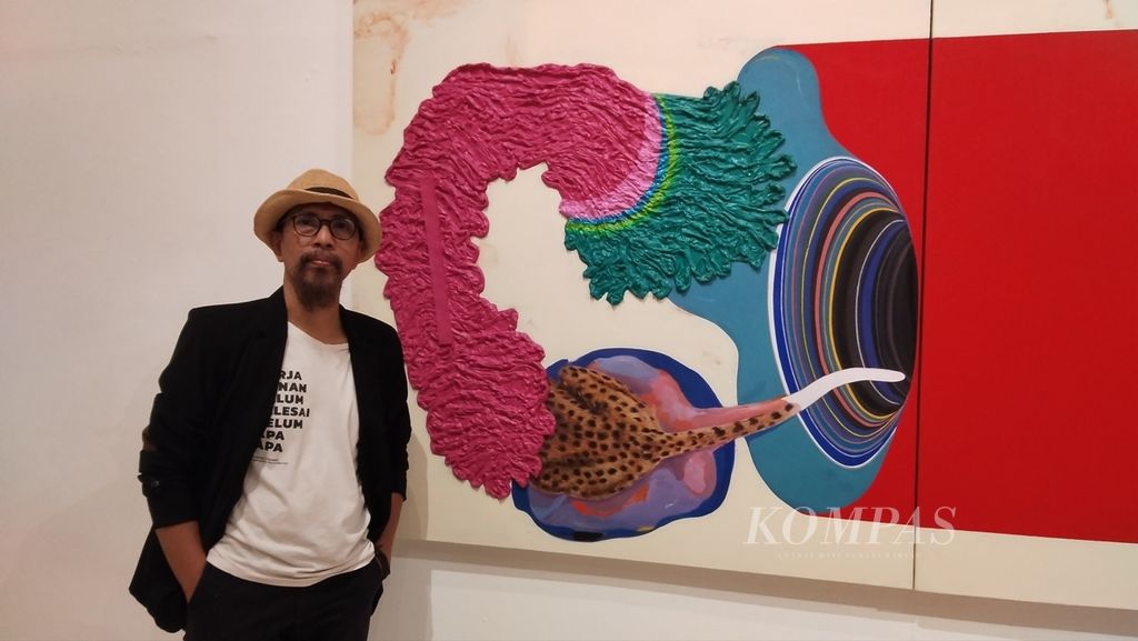 Seniman Gusmen Heriadi berpose di depan karyanya yang berjudul ”Nafas Semesta No. 05” yang ditampilkan dalam pameran Balistik24 di Jogja Gallery, Kota Yogyakarta, Jumat (16/2/2024).