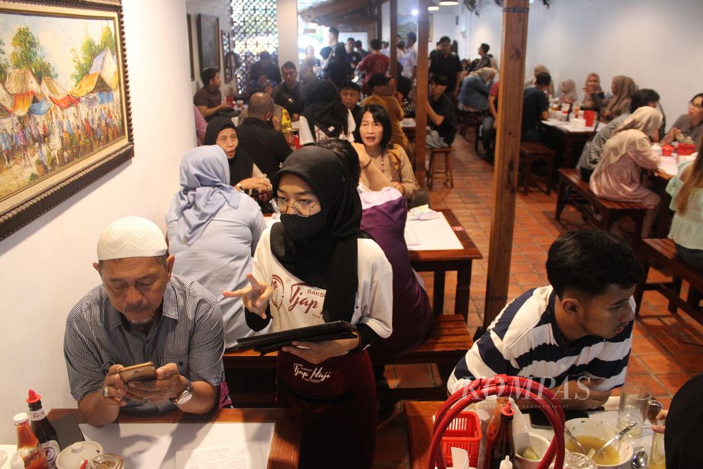 Pramusaji melayani pembeli yang memilih menu Bakso Tjap Haji, Jalan Burangrang, Kota Bandung, Jawa Barat, Jumat (12/4/2024). Selama momen Lebaran, para pembeli yang menikmati sajian aneka bakso di sini mencapai 2.000 orang setiap harinya.