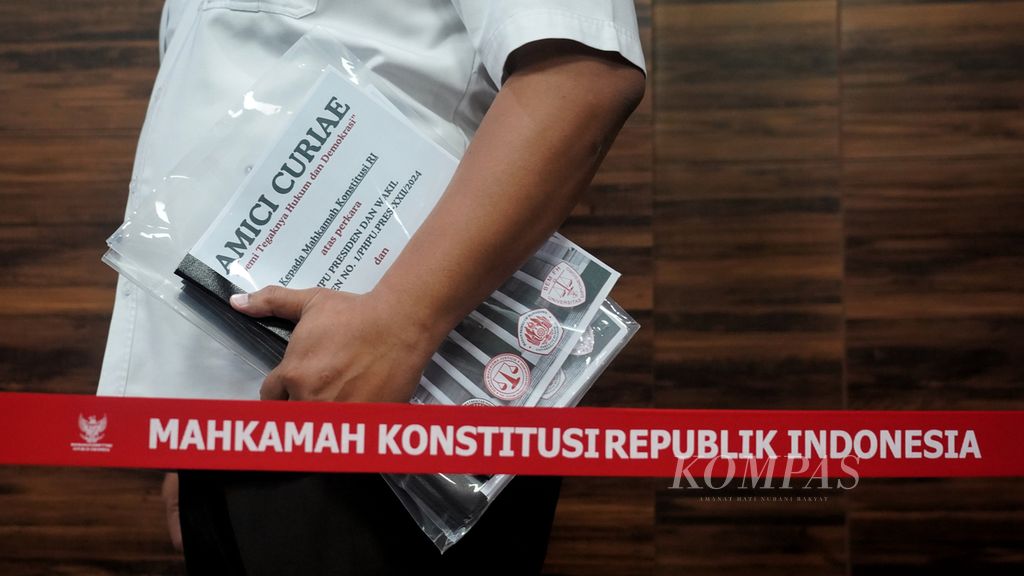Petugas Mahkamah Konstitusi membawa lembaran Amicus Curiae yang diserahkan perwakilan mahasiswa fakultas hukum Univeraitas Gadjah Mada, Universitas Diponegoro, dan Universitas Padjadjaran yang hadir di Mahkamah Konstitusi, Jakarta, untuk diserahkan kepada Ketua Mahkamah Konstitusi, Selasa (16/4/2024). 