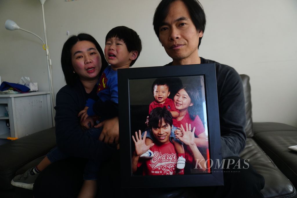 Lily Lumintang (43, kiri), Martin Cahyo (45), dan anak bungsu mereka, Raphael (3), berfoto dengan memegang foto masa kecil Jonathan, anak sulung mereka, ketika ditemui di rumah mereka di Kew, di timur Melbourne, Australia, Sabtu (24/8/2024). Permohonan residensi permanen keluarga mereka ditolak Pemerintah Australia karena Jonathan, yang kini berusia 14 tahun dan tinggal di Surabaya, memiliki <i>cerebral palsy</i> dan disebut akan menjadi beban anggaran bagi pemerintah.