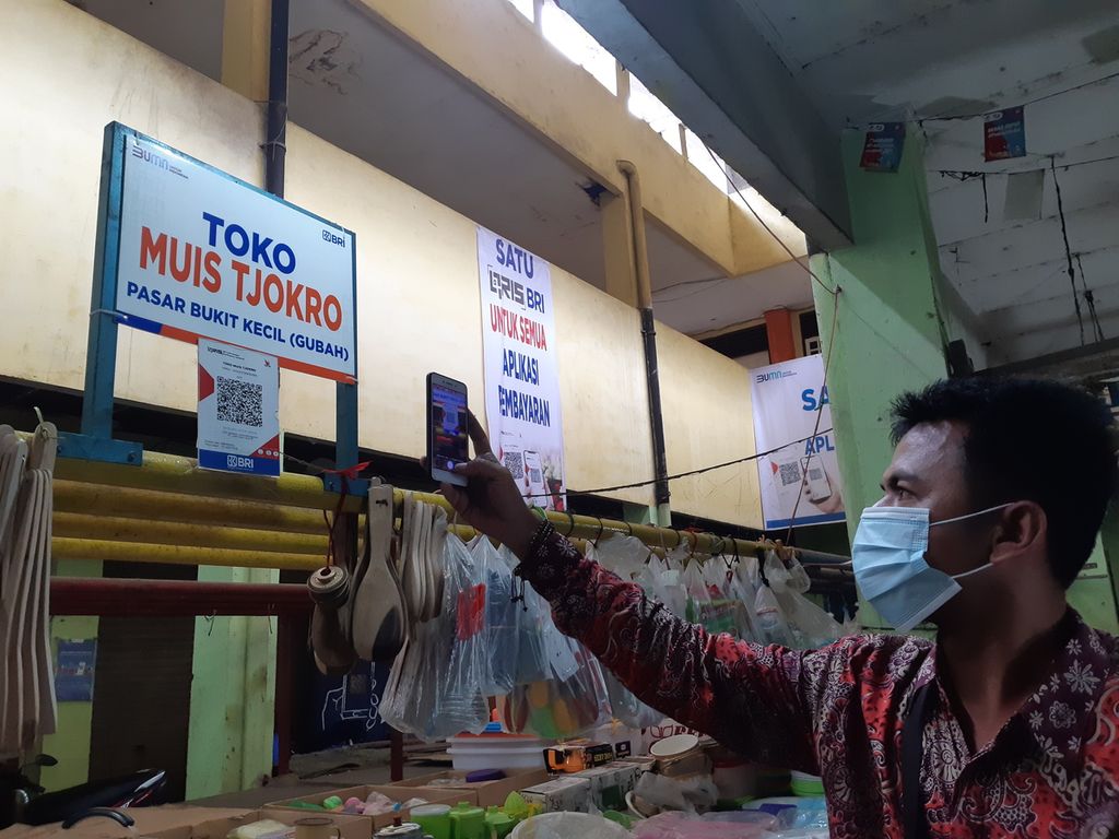 Seorang pelanggan sedang mencoba fasilitas Quick Response Code Indonesian Standard (QRIS) di Pasar Gubah, Palembang, Sumatera Selatan, Kamis (23/12/2021). Fasilitas QRIS sudah mulai digalakkan. Namun, butuh sosialisasi yang lebih masif untuk membiasakan warga menggunakannya.