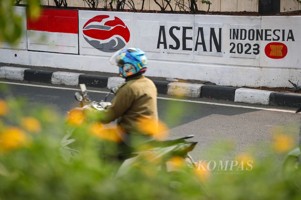 Pengendara sepeda motor melintasi mural logo "ASEAN Indonesia 2023" di Jalan Arteri Pondok Indah, Jakarta Selatan, Kamis (10/8/2023). Berbagai ornamen bernuansa ASEAN menghiasi sudut-sudut kota Jakarta untuk menyambut Konferensi Tingkat Tinggi Ke-43 ASEAN yang akan digelar di Jakarta pada 5-7 September 2023. 