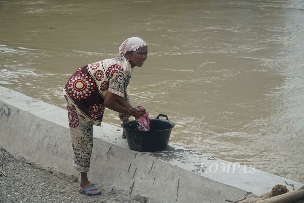 Warga mencuci pakaian di Batang Merao di Desa Tanjung, Kecamatan Hamparan Rawang, Kota Sungai Penuh, Jambi, Sabtu (20/1/2024). Warga mencuci di sungai karena kesulitan air bersih akibat banjir yang dipicu meluapnya Batang Merao sejak awal tahun.