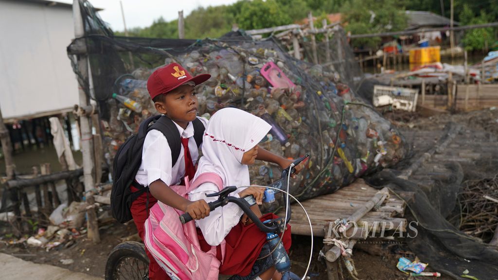 Pelajar melewati sampah plastik pesisir yang dikumpulkan di Desa Pantai Mekar, Kecamatan Muaragembong, Kabupaten Bekasi, Jawa Barat, Kamis (27/10/2022). 