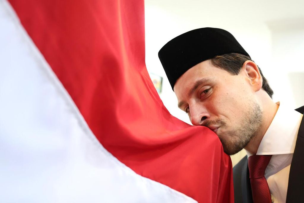 Pemain sepak bola Thom Haye mencium bendera Indonesia seusai disumpah menjadi WNI di Kantor Wilayah Kemenkumham DKI Jakarta, Rabu (19/3/2024) dini hari WIB. Thom bermain di posisi gelandang bertahan.