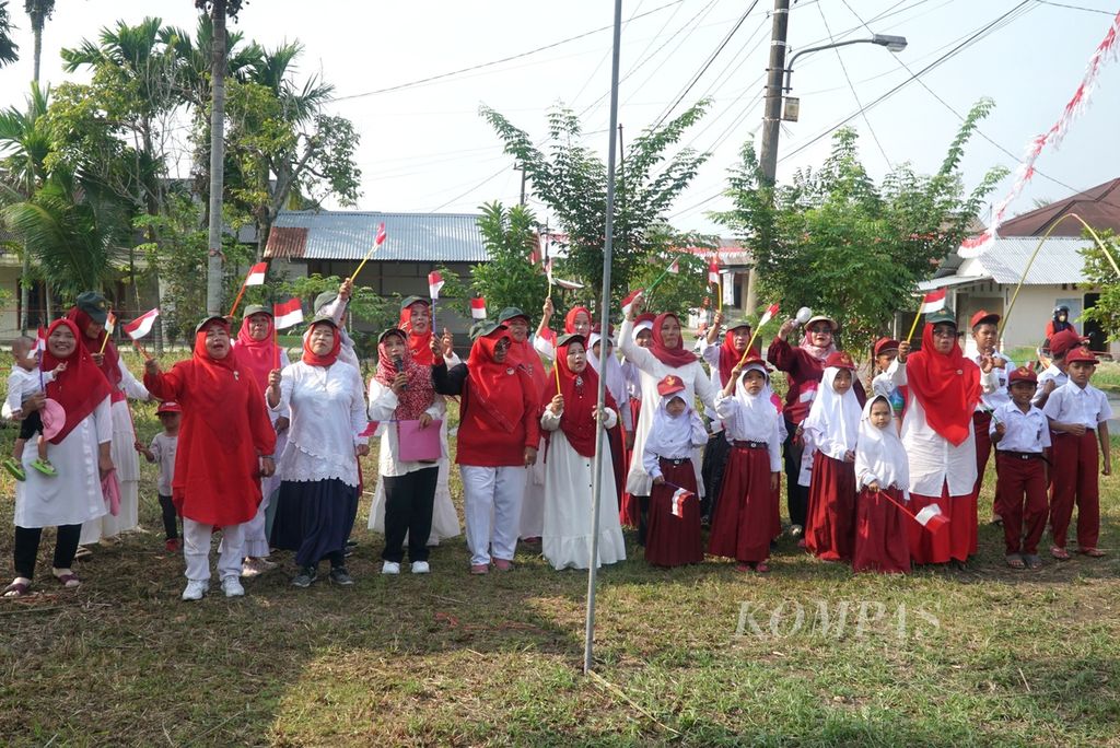 Warga menyanyikan lagu kebangsaan sembari mengibar-ngibarkan bendera Merah-Putih kecil usai upacara bendera dalam peringatan Hari Ulang Tahun Kemerdekaan Ke-78 Republik Indonesia di RT 004 RW 005, Kelurahan Dadok Tunggul Hitam, Kota Padang, Sumatera Barat, Kamis (17/8/2023).
