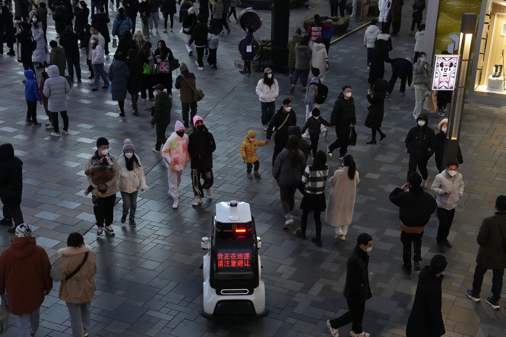 Robot polisi sedang berpatroli di dekat kerumunan warga yang kembali memenuhi mal setelah pelonggaran pembatasan pandemi di Beijing, China, Minggu (1/1/2023). Sambil berkeliling, robot itu mengatakan, "Saya sedang berpatroli. Harap berhati-hati dan memberi jalan". 
