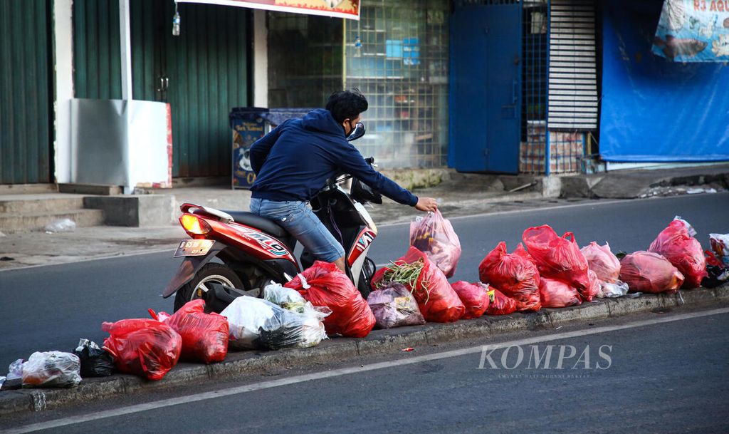 Warga yang mengendarai sepeda motor berhenti di tengah jalan untuk membuang sampah di separator Jalan Raden Patah, Ciledug, Kota Tangerang, Banten, Jumat (7/1/2022). 