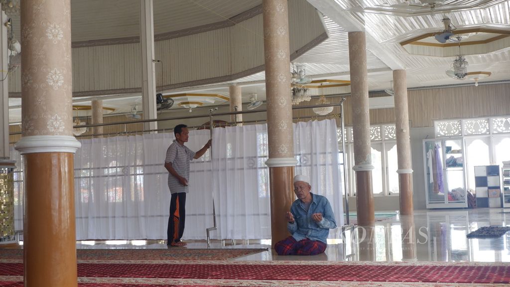 Suriansyah (57), marbot atau kaum masjid (berdiri), menyalakan penyejuk ruangan di Masjid Al-Amin, Banua Anyar, Banjarmasin, Kalimantan Selatan, Kamis (21/3/2024).