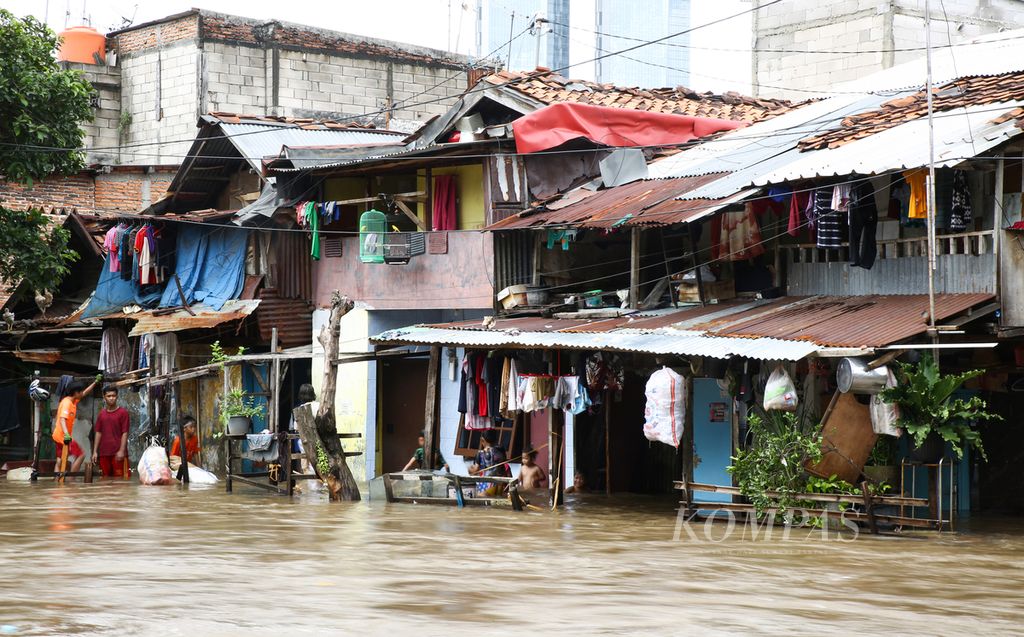 Anak-anak bermain air banjir yang merendam hunian di bantaran Kali Krukut di kelurahan Karet Tengsin, Tanah Abang, Jakarta Pusat, Selasa (25/2/2020). Banjir akibat curah hujan yang tinggi ini tidak hanya merendam kawasan permukiman, tetap juga memutus akses jalan di sejumlah wilayah di Jakarta, Bekasi, dan Tangerang.