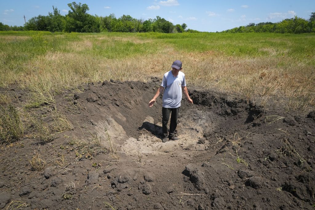 Seorang petani di desa Ptyche, Donetsk, Serhiy, memperlihatkan kawah bekas ledakan bom Rusia di ladangnya, Minggu (12/6/2022). 