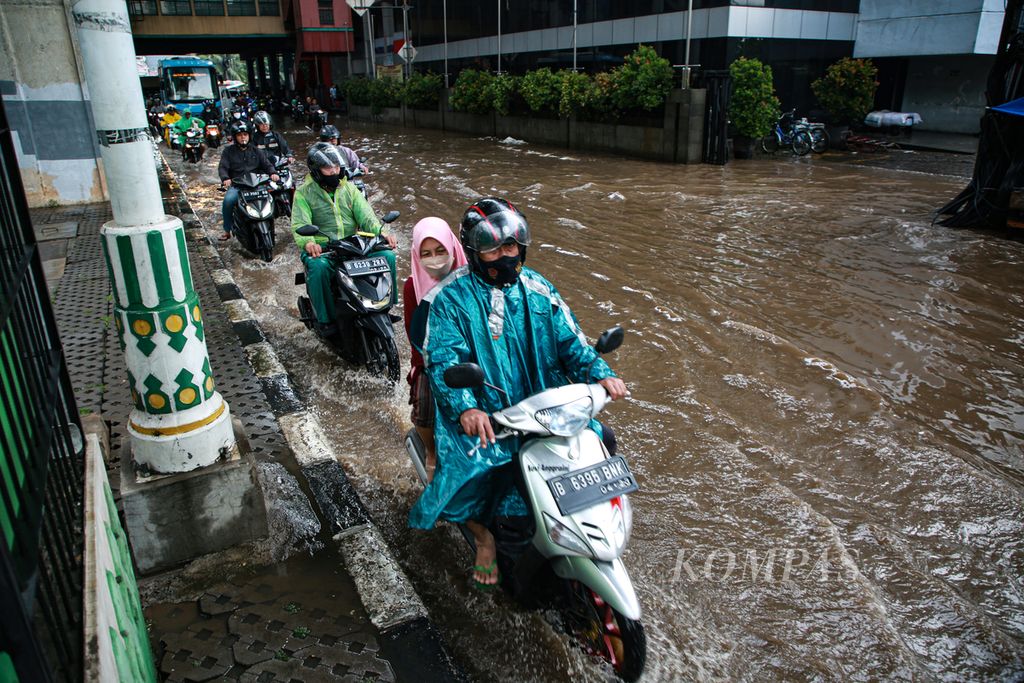 Antrean pengendara sepeda motor yang berjalan melewati genangan tepat di depan Pusat Grosir Metro Cipulir, Jakarta Selatan, Senin (7/11/2022). Genangan yang muncul selepas hujan tersebut menyebabkan kemacetan.
