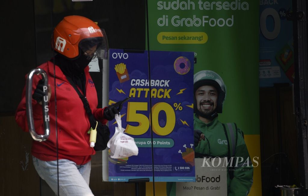 Promosi <i>cashback</i> atau imbal tunai pembayaran menggunakan layanan dompet digital OVO terpasang di pintu masuk salah satu gerai makanan cepat saji di kawasan Tanjung Duren, Jakarta Barat, Selasa (5/1/2021). 