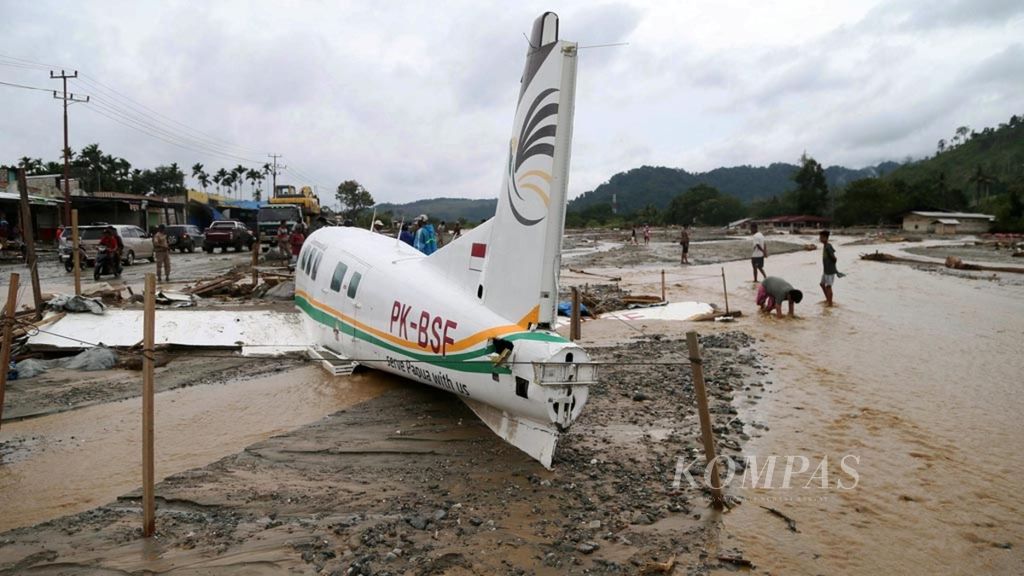 Pesawat twin otter yang terseret banjir bandang masih terbelangkai di Lapangan Terbang Adventis, Doyo, Sentani, Papua, Selasa (19/3/2019). Hingga hari keempat pasca banjir, jumlah korban meninggal dunia mencapai 92 orang, 75 hilang dan sebanyak 8.057 orang mengungsi. Banjir melanda tiga distrik yaitu Sentani, Waibu, dan Sentanu.KOMPAS/HENDRA A SETYAWAN (HAS)19-03-2019