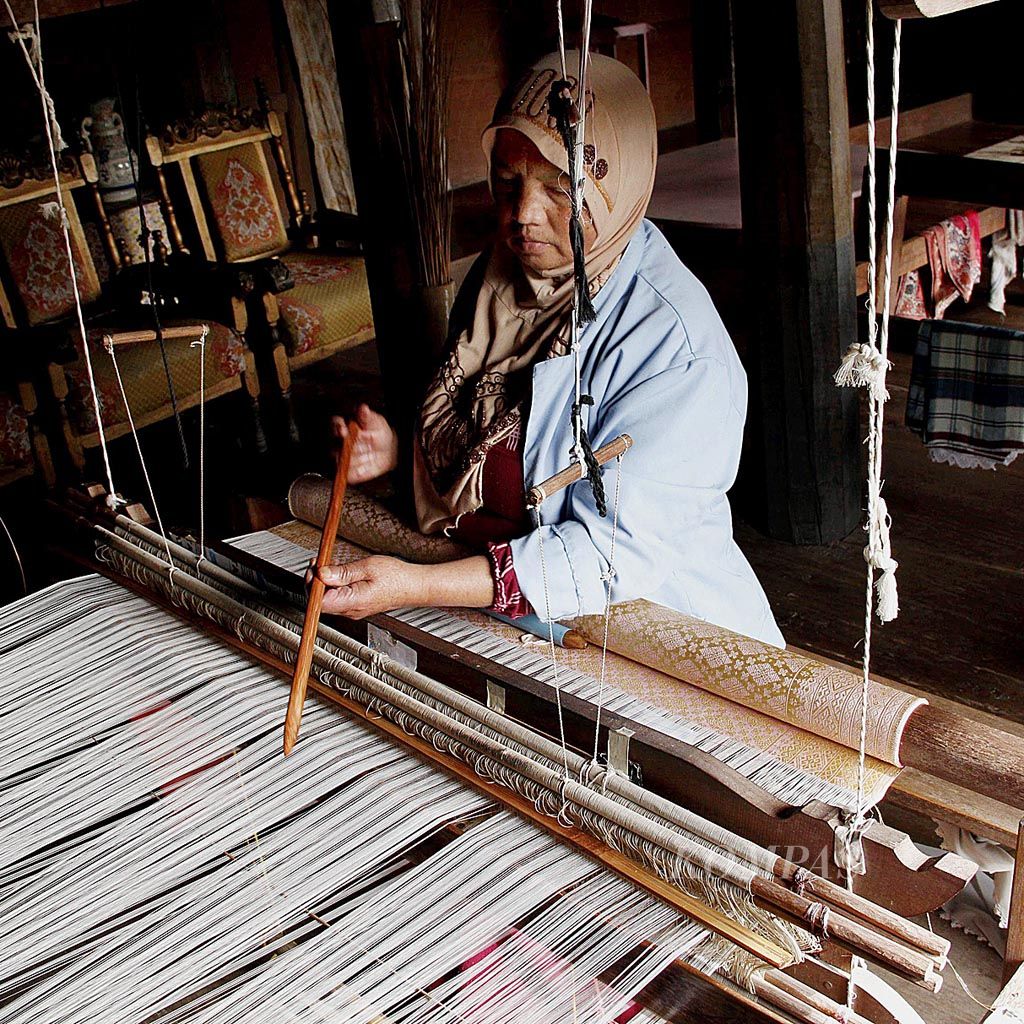 Susmita, salah seorang perajin songket dari Nagari Pandai Sikek, menenun salah satu pesanan pelanggannya di rumah tenun Puti Bungsu. Menenun songket merupakan keahlian yang diturunkan leluhur Minangkabau kepada perempuan yang tinggal di rumah gadang. 