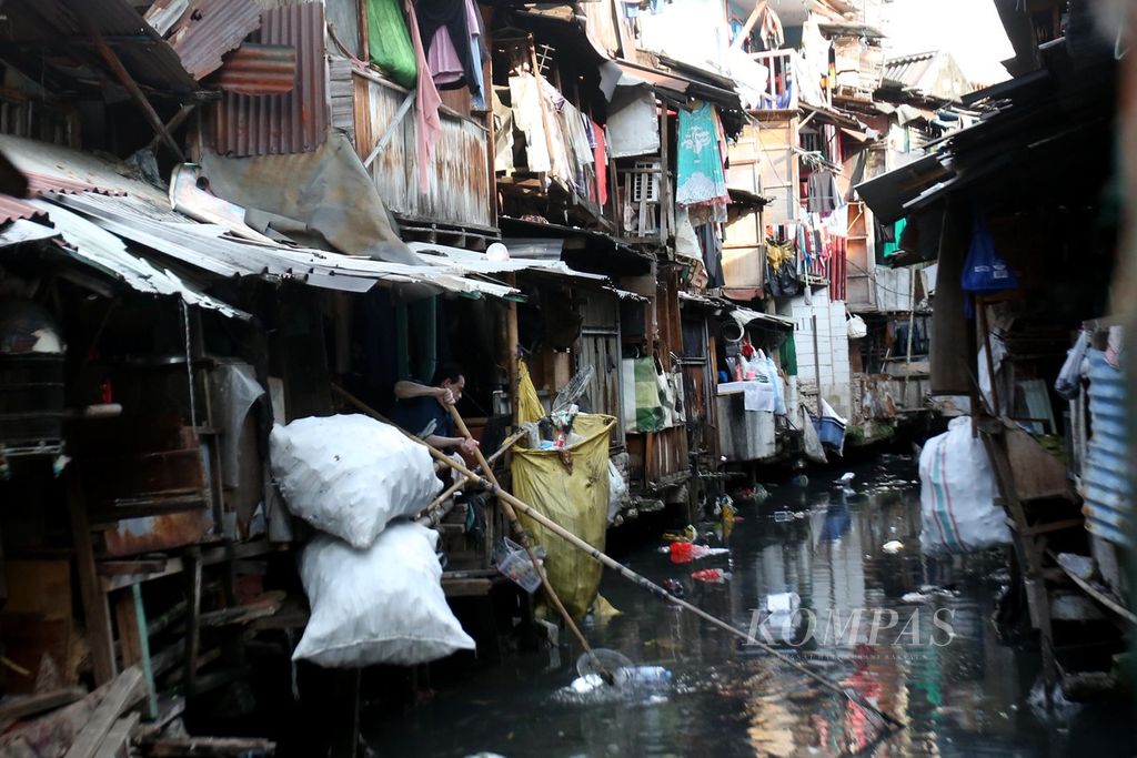 Seorang warga memulung sampah di Kali Krukut yang membelah permukiman semipermanen padat penduduk di kawasan Kebon Melati, Tanah Abang, Jakarta Pusat, Kamis (27/6/2024). Berdasarkan data BPS DKI Jakarta, dari total penduduk DKI Jakarta, 0,89 persen atau setara 95.668 jiwa di antaranya berada ke dalam golongan kemiskinan ekstrem. 