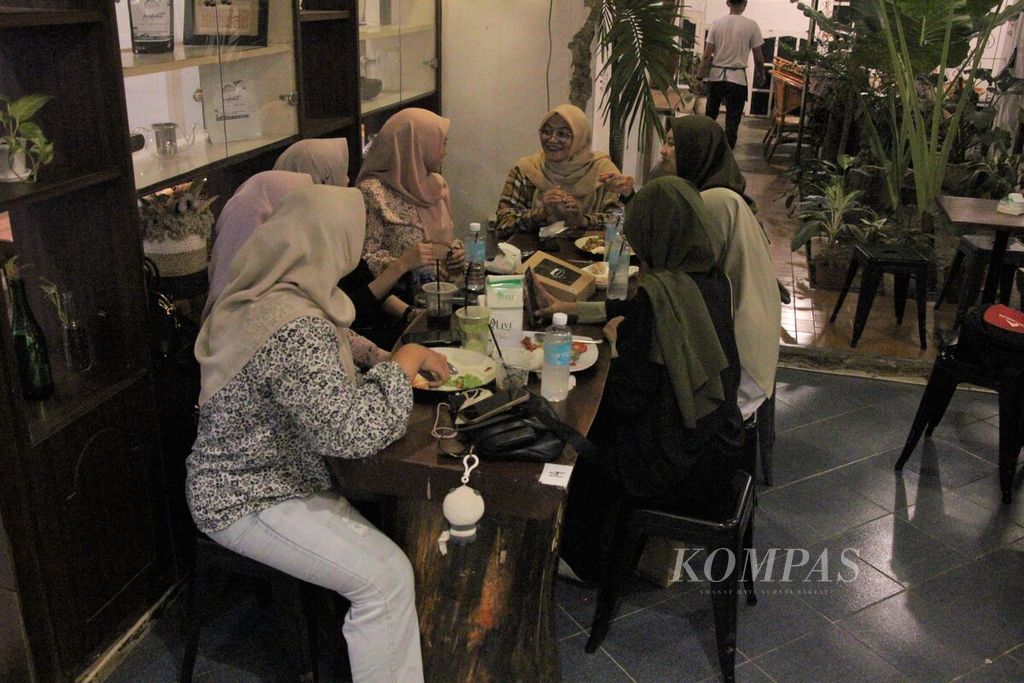Pengunjung kafe sedang menikmati makanan dan minuman bersama, Jumat (24/2/2023). Budaya <i>ngopi</i> telah mendorong para pebisnis untuk membuat konsep warung/kafe lebih kekinian.