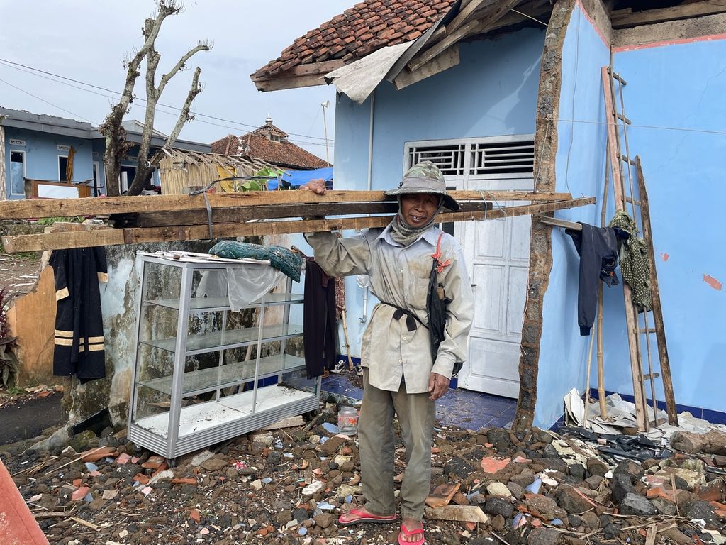 Penyintas gempa Cianjur, Lili Sadeli (66), mengambil kayu dari rumahnya yang ambruk di Kampung Rawacina RT 002 RW 015, Desa Nagrak, Kecamatan Cianjur. Tak jauh dari rumahnya, Lili mendirikan tenda yang kemudian terseret banjir pada Senin (20/3/2023)
