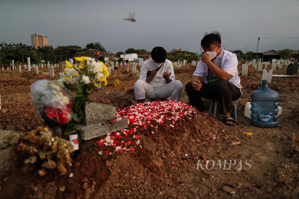 Fauzan (23, kanan) dan Fathan (15) berziarah ke makam ibunya yang meninggal karena Covid-19 di TPU Rorotan, Jakarta Utara, Jumat (20/8/2021). Covid-19 menyebabkan banyak anak yang harus kehilangan orangtuanya