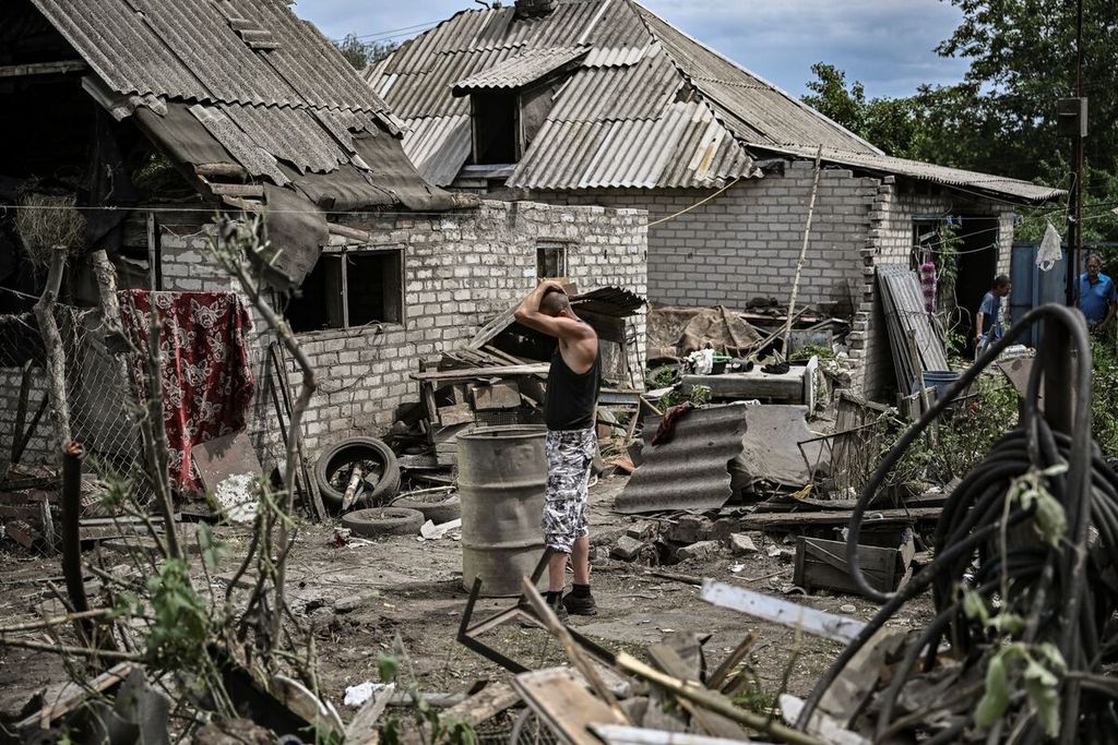 Seorang warga berdiri di halaman rumahnya yang porak poranda setelah ibu dan ayah tirinya meninggal akibat gempuran artileri di kota Lysychansk, wilayah Donbas, Ukraina timur, 13 Juni 2022. 