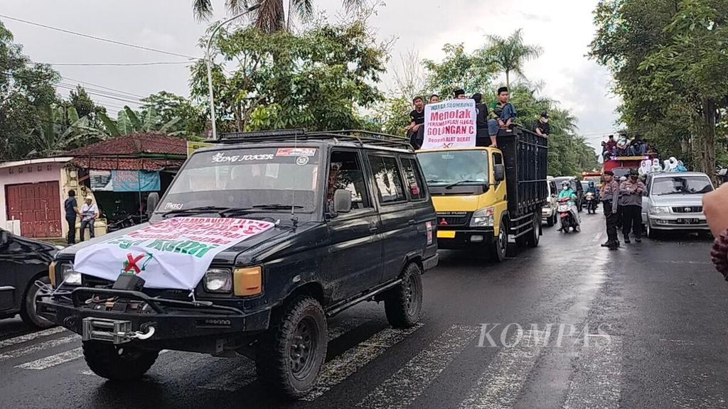 Iring-iringan kendaraan dengan tempelan spanduk berisi pernyataan menolak penambangan pasir ilegal di kawasan Merapi melintas di jalan raya di Kelurahan Sawitan,. Kecamatan Mungkid, Kabupaten Magelang, Jateng, Jumat (24/2/2023).