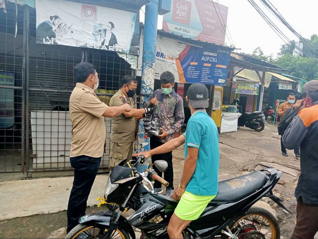 Petugas dari Kecamatan Pondok Aren, Tangerang Selatan, Banten, menertibkan warga yang tidak mengenakan masker saat beraktivitas di ruang publik pada Februari 2022. Warga ditegur sekaligus diberikan masker.