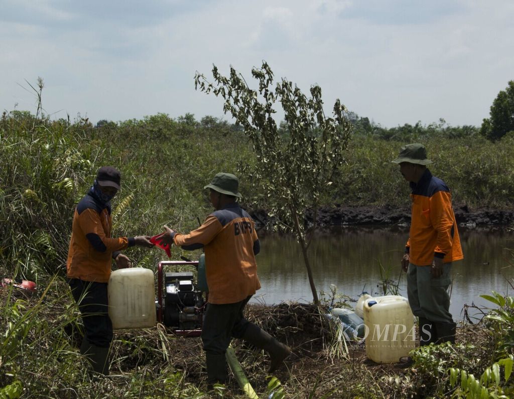 Petugas pemadam dari BPBD Riau sedang mengecek mesin pompa dan mengisi bahan bakar di embung Desa Rimbo Panjang, awal Oktober 2019. Sumber air embung berjarak sekitar 1 kilometer dari lokasi kebakaran.