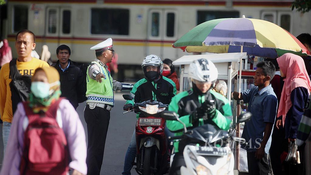 Polisi memperingatkan pengemudi ojek dalam jaringan (daring) agar menunggu penumpang di tempat yang sudah ditentukan di dekat Stasiun Karet, Jakarta, Senin (2/3). Di satu sisi ojek daring menjadi solusi mobilitas warga di tengah kemacetan, tetapi di sisi lain menjadi penyebab kesemrawutan lalu lintas.