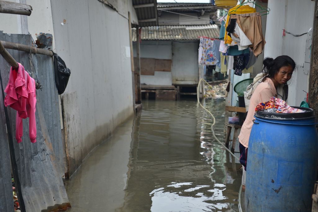 Warga beraktivitas di tengah genangan banjir rob di Blok Empang, Penjaringan, Jakarta Utara, Senin (26/12/2022). 