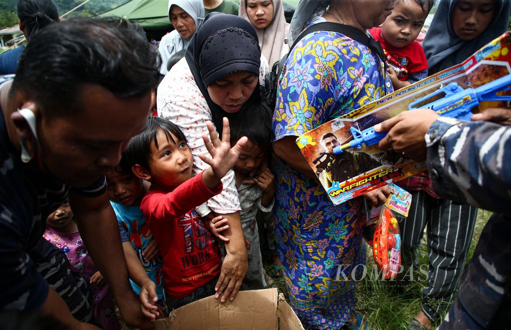 Personel TNI membagikan mainan kepada anak-anak yang mengikuti program pemulihan trauma di sekitar tenda pengungsian di Desa Pakuon, Kecamatan Sukaresmi, Kabupaten Cianjur, Jawa Barat, Minggu (27/11/2022). Dalam kesempatan itu, personel TNI Angkatan Laut mengajak anak-anak bermain dan membagikan mainan dan paket makanan.