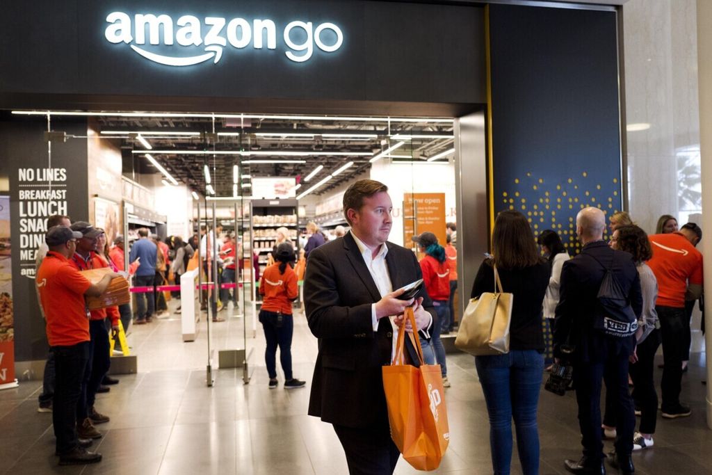 FILE - In this May 7, 2019, file photo a customer carries his shopping bag as she walks out of a newly-opened Amazon Go store in New York. Amazon.com Inc. reports financial earnings on Thursday, July 25. (AP Photo/Mark Lennihan, File)
