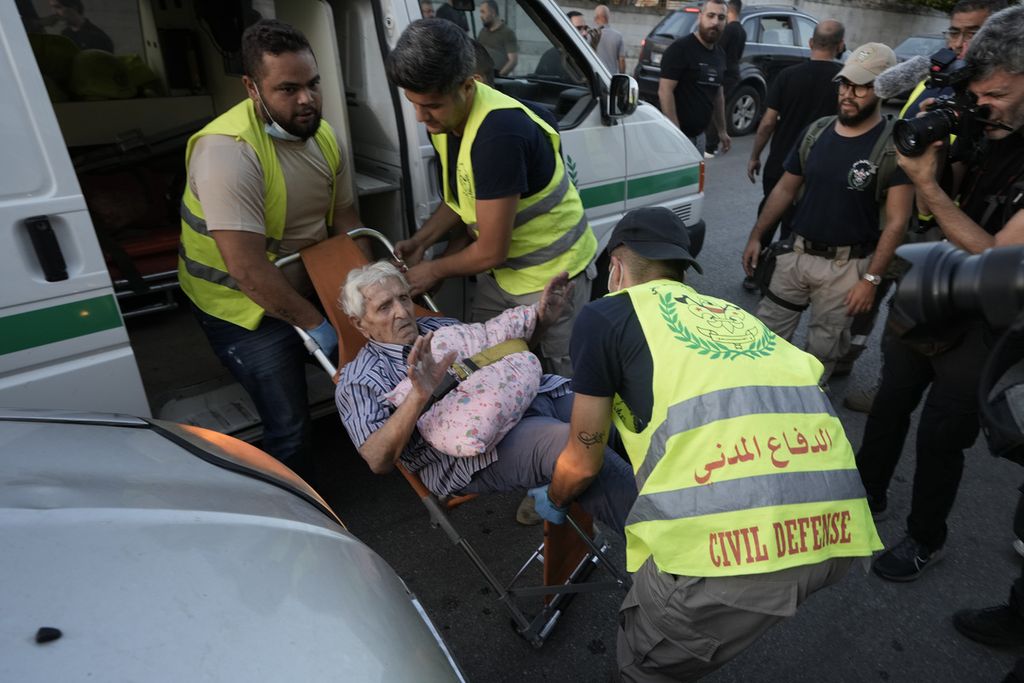 Petugas pertahanan sipil Lebanon mengangkat seorang pria lansia, yang mengungsi dari wilayah selatan, saat pria itu tiba di tempat perlindungan di sebuah sekolah di Beirut, Lebanon, Senin (23/9/2024). 