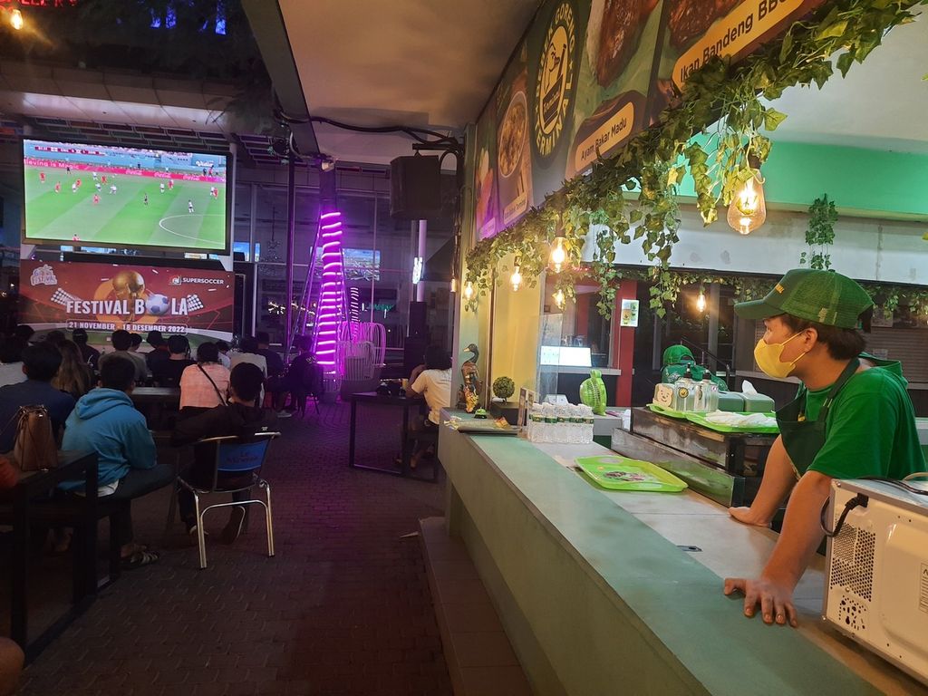 Para penggemar sepak bola menyaksikan laga Inggris lawan Iran dalam Piala Dunia 2022 di Sedayu City, Kelapa Gading, Jakarta, Senin (21/11/2022). Seluruh mata memandang pertandingan tersebut, termasuk para pedagang makanan.