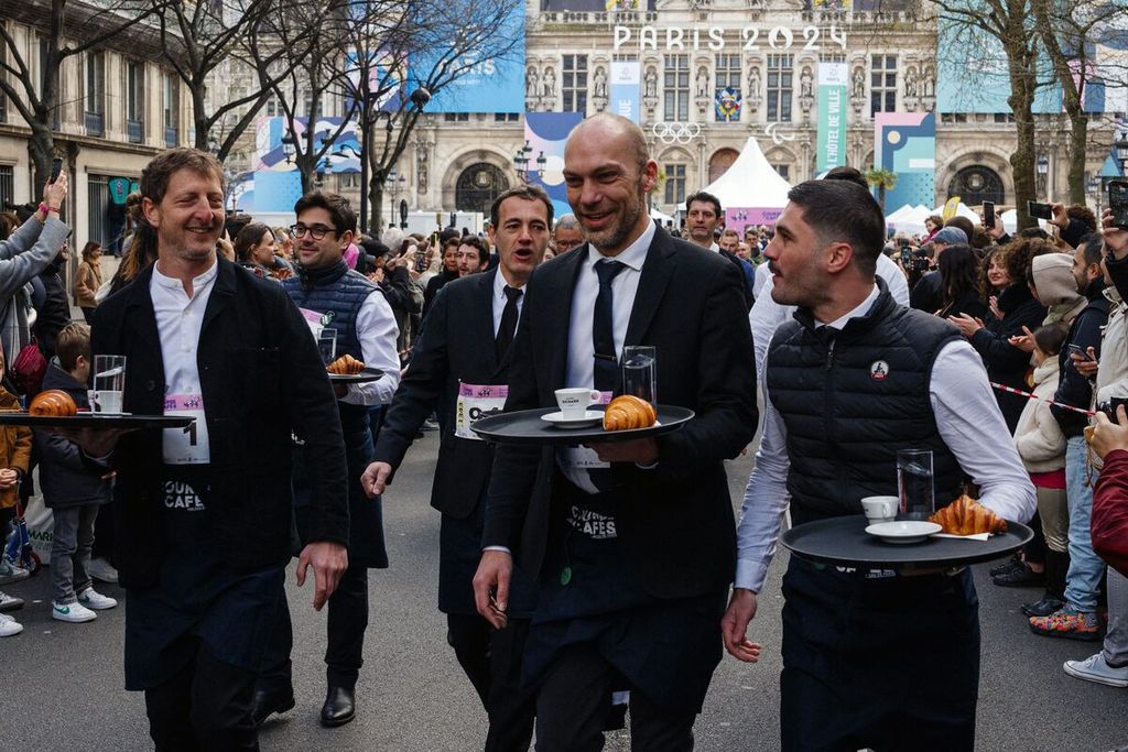 Para pramusaji mengikuti perlombaan tradisional Course des Cafes atau perlombaan kafe yang berlangsung di depan Balai Kota Paris, Perancis, Minggu (24/3/2024). 