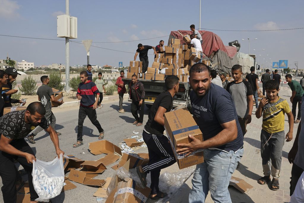 Warga membongkar paket bantuan, sementara anggota rombongan memuat kembali kotak-kotak yang jatuh ke truk pembawa bantuan kemanusiaan yang memasuki Jalur Gaza selatan dari Mesir melalui perbatasan Rafah dengan Mesir, di Jalur Gaza selatan, Palestina, Kamis (2/11/2023). 