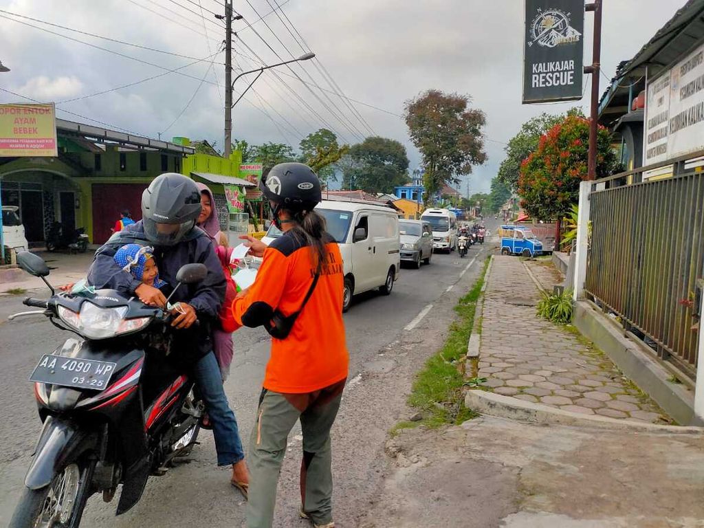 Petugas Tim BPBD Wonosobo membagikan masker kepada warga setelah abu vulkanik Gunung Merapi terbawa angin hingga Wonosobo, Jawa Tengah, Sabtu (11/3/2023).
