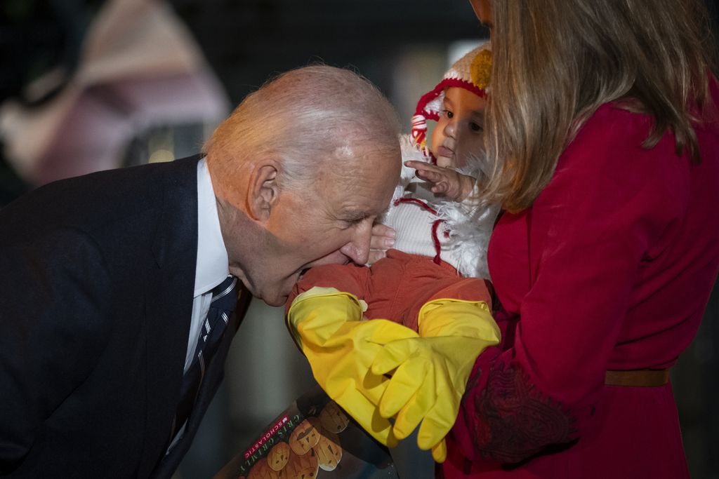 Presiden AS Joe Biden terlihat bercanda dengan menggigit kaki seorang bayi saat ia dan Ibu Negara Jill Biden menjamu para siswa, para putra anggota militer, dan keluarga-keluarga sekitar Gedung Putih menjelang perayaan Halloween di Halaman Selatan Gedung Putih, Washington DC, AS, Rabu (30/10/2024). 