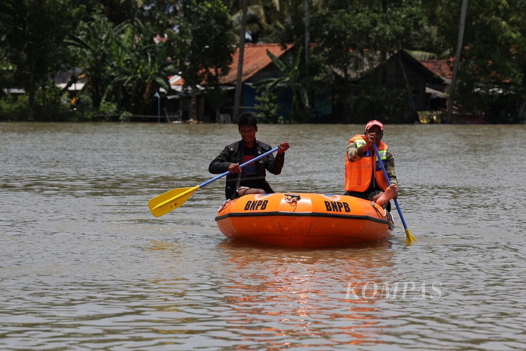 Warga menggunakan perahu untuk membantu evakuasi korban banjir di Desa Kedungmulyo, Butuh, Purworejo, Jawa Tengah, Rabu (16/3/2022). 