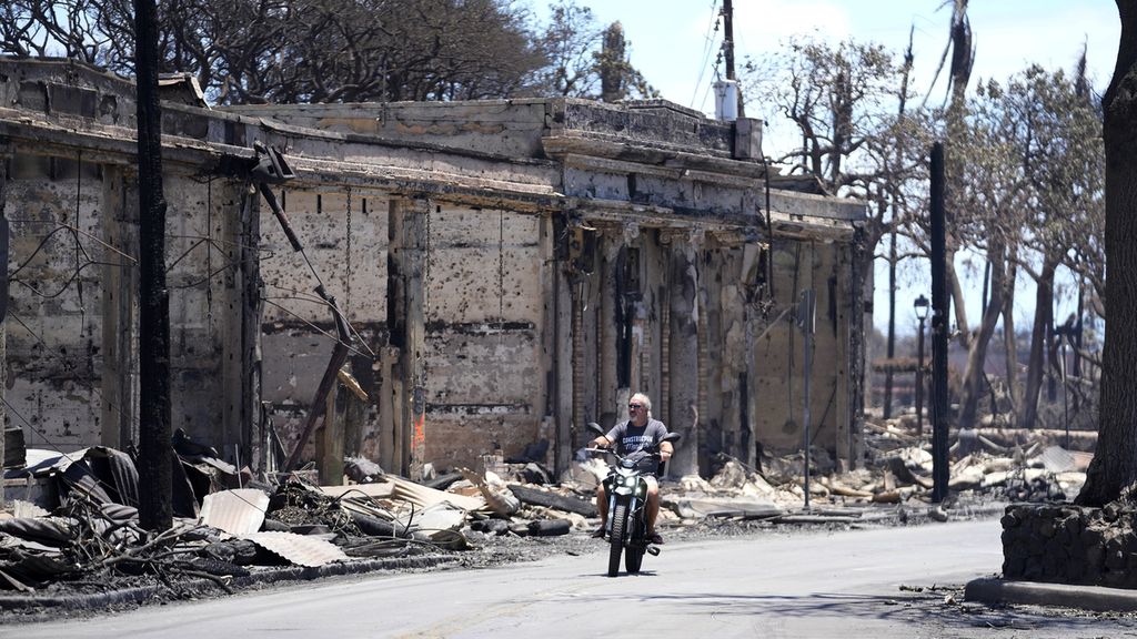 Seorang pengendara sepeda motor melihat-lihat rumah dan bangunan yang terbakar di Lahaina, Hawaii, Jumat (11/8/2023). Pemerintah setempat kini tengah mengkaji ulang sistem peringatan dini yang dinilai tidak berfungsi saat kebakaran mulai terjadi, Selasa (8/8/2023) sore. 