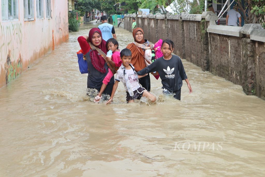 Warga berjalan ke pengungsian akibat banjir luapan Sungai Ciberes di Desa Gunungsari, Kecamatan Waled, Kabupaten Cirebon, Jawa Barat, Sabtu (22/1/2022) siang. Sekitar 200 warga mengungsi ke balai desa setempat. 