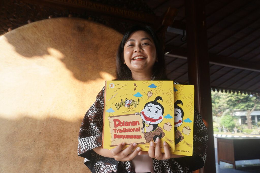 Rida Purnama Sari menunjukkan buku <i>Lithong! Dolanan Tradisional Banyumasan</i> di Purwokerto, Banyumas, Jawa Tengah, Kamis (22/6/2023).